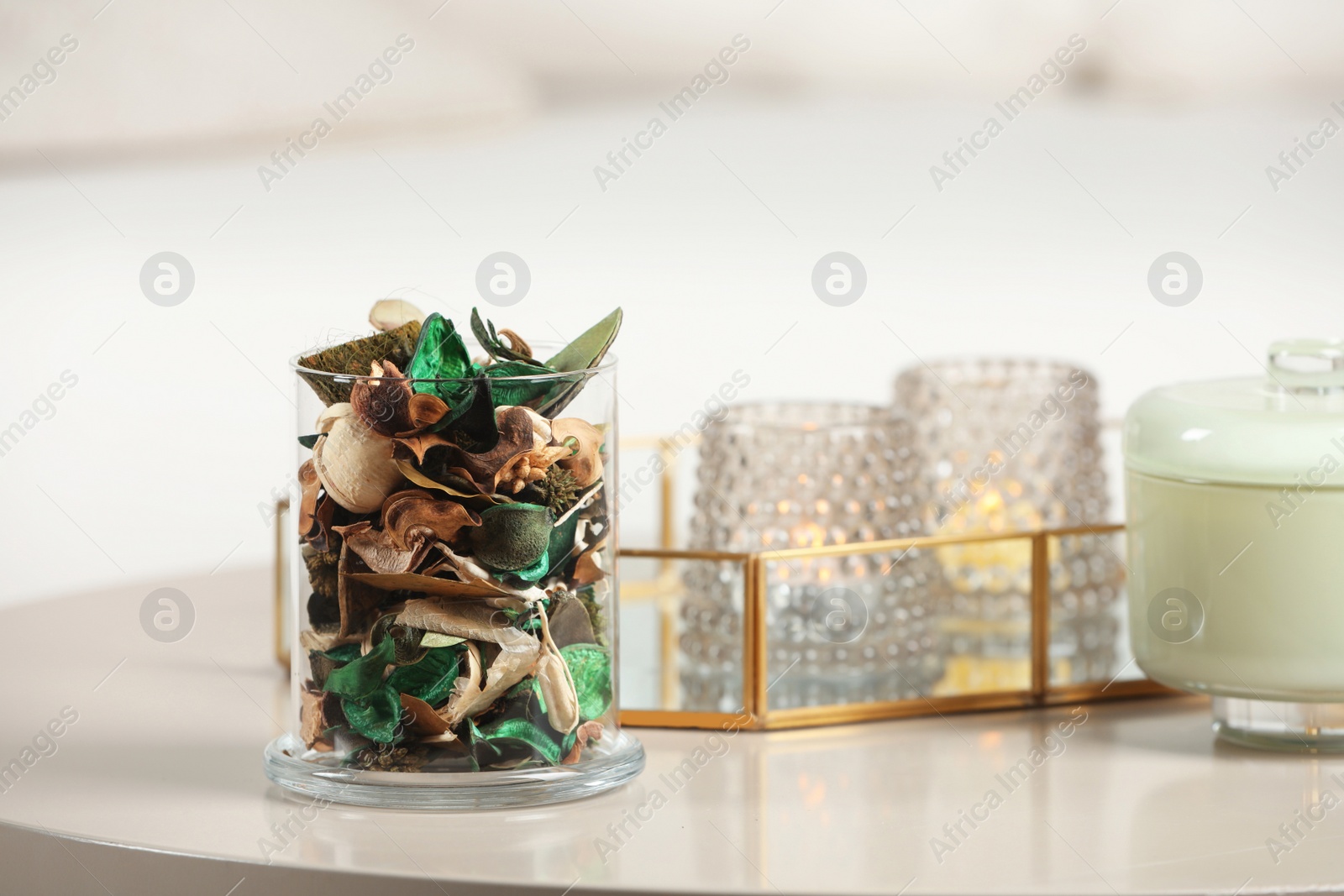 Photo of Aromatic potpourri of dried flowers in glass jar on white table indoors