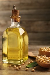 Photo of Glass bottle of oil and soybeans on wooden table