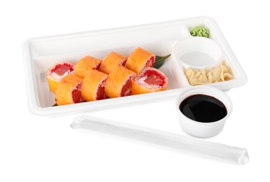 Food delivery. Plastic container with delicious sushi rolls near bowl of soy sauce and chopsticks on white background