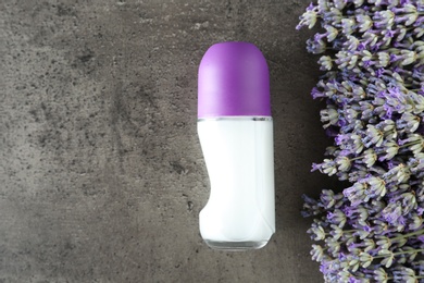 Female deodorant and lavender flowers on grey stone background, flat lay