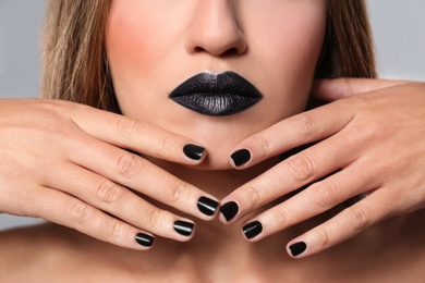 Photo of Beautiful woman with stylish nail polish on grey background, closeup