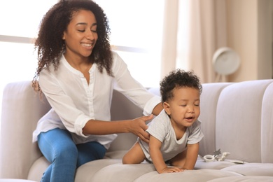 Photo of African-American woman with her baby in living room. Happiness of motherhood