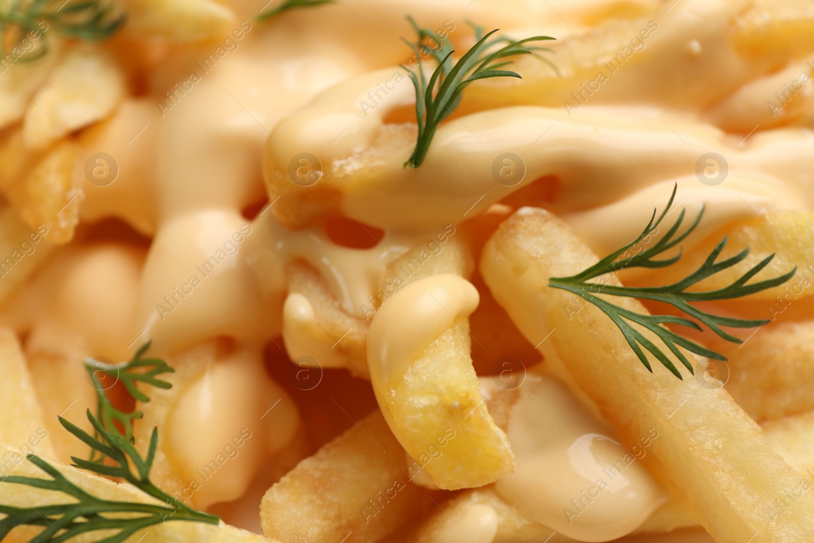 Photo of Delicious french fries with cheese sauce and dill as background, closeup