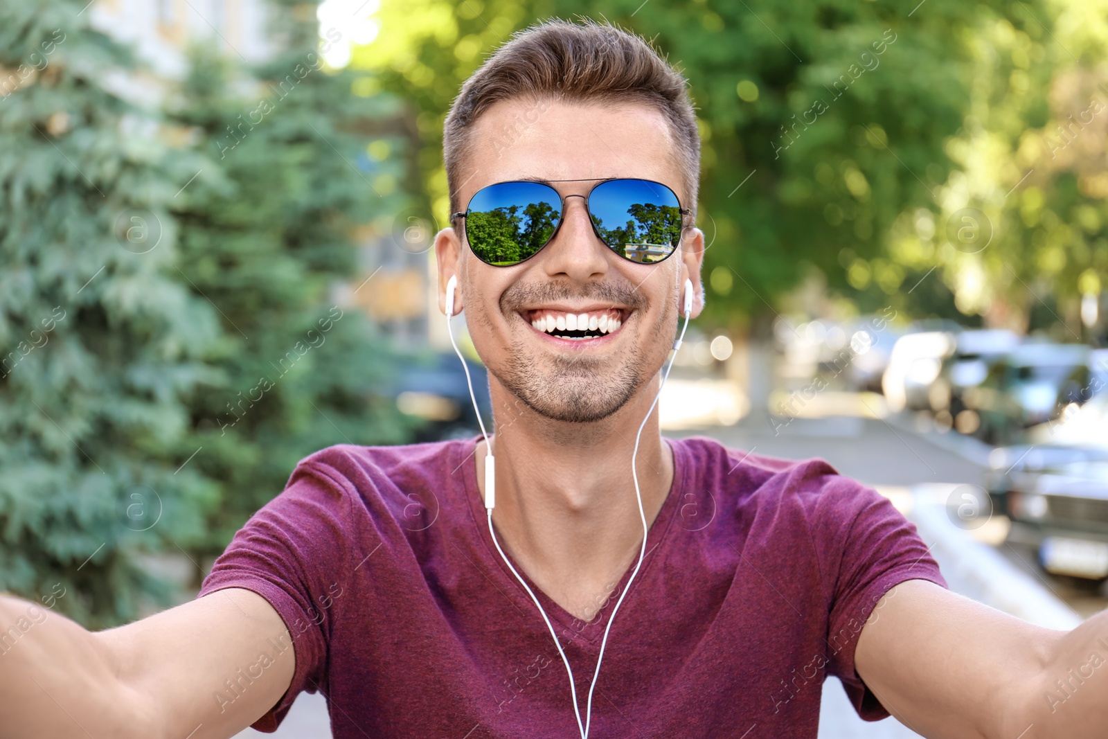 Photo of Young man in sunglasses taking selfie outdoors