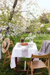Photo of Stylish table setting with beautiful spring flowers, tea and croissants in garden