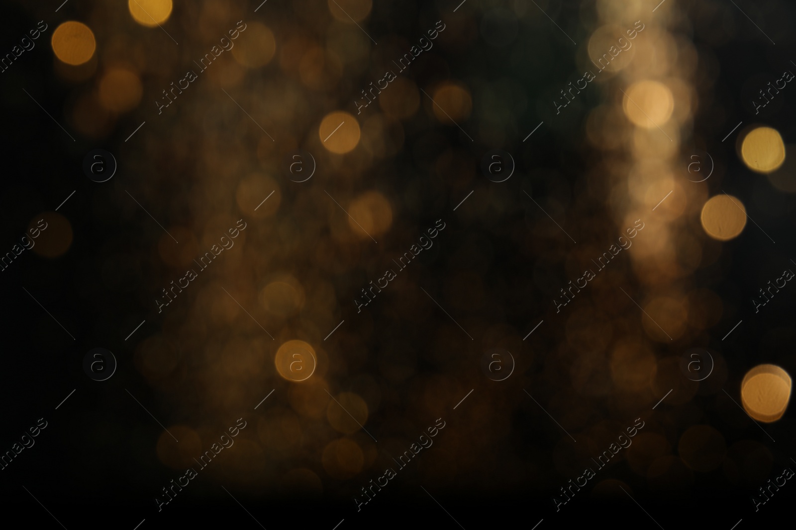 Photo of Blurred view of golden lights on black background. Bokeh effect