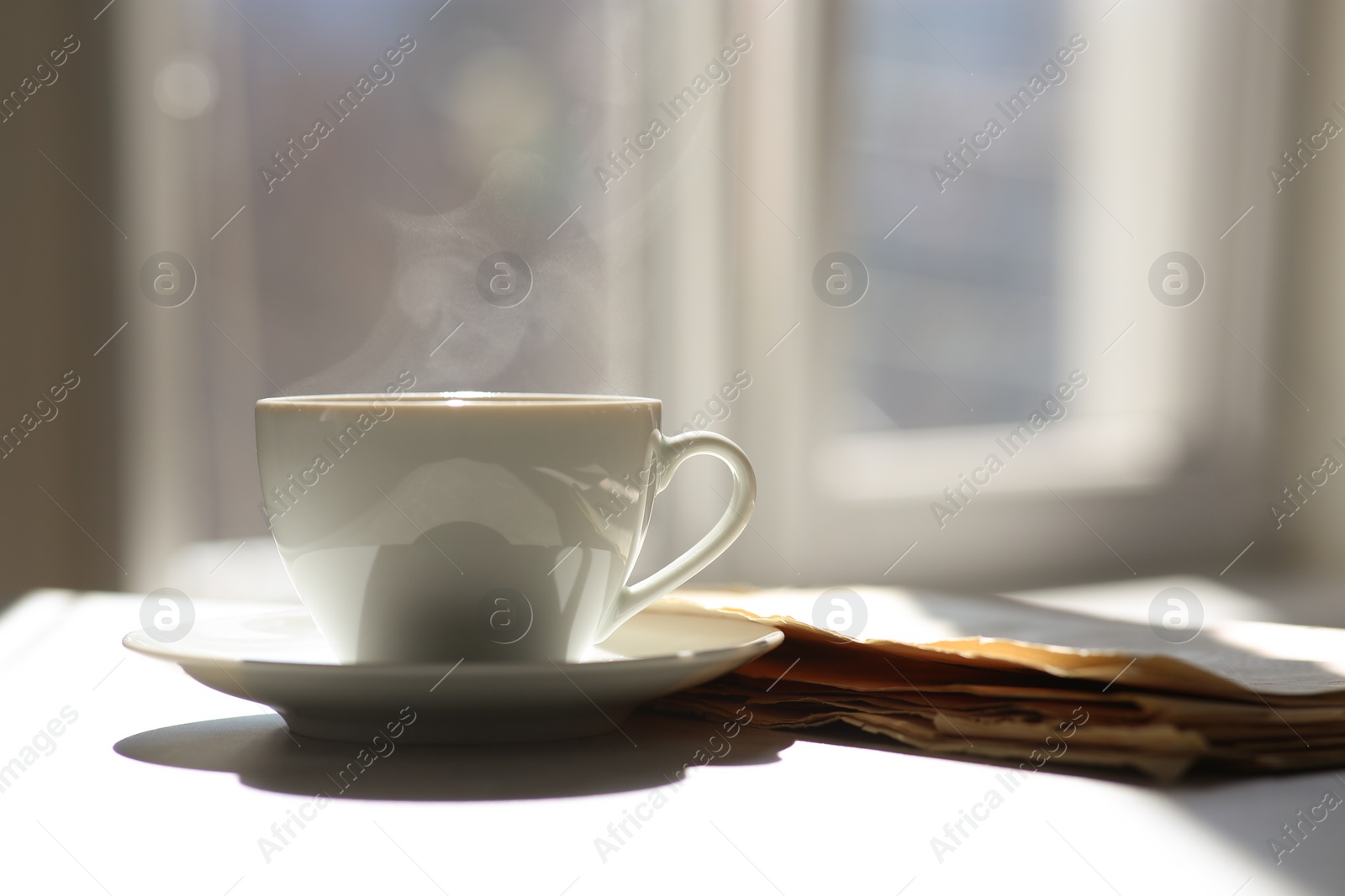 Photo of Delicious coffee and newspaper on sunlit table, space for text. Good morning