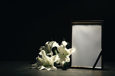 Photo of Funeral photo frame and lily flowers on dark background