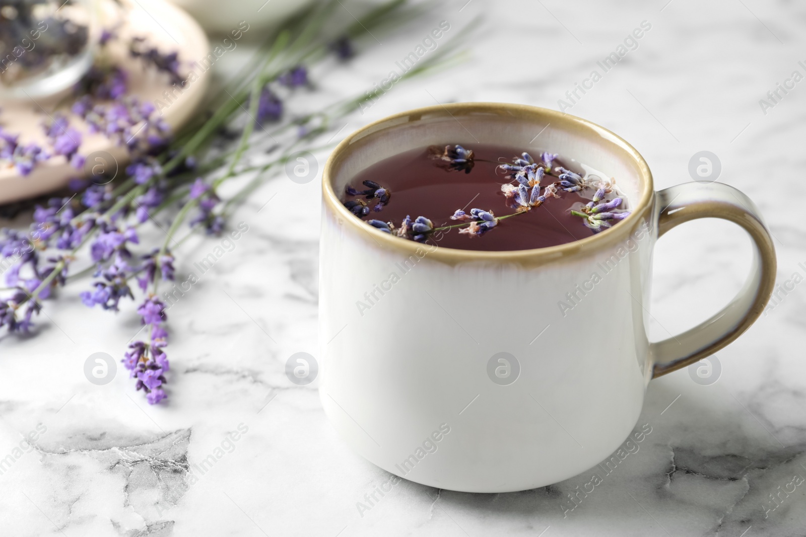 Photo of Fresh delicious tea with lavender and beautiful flowers on white marble table