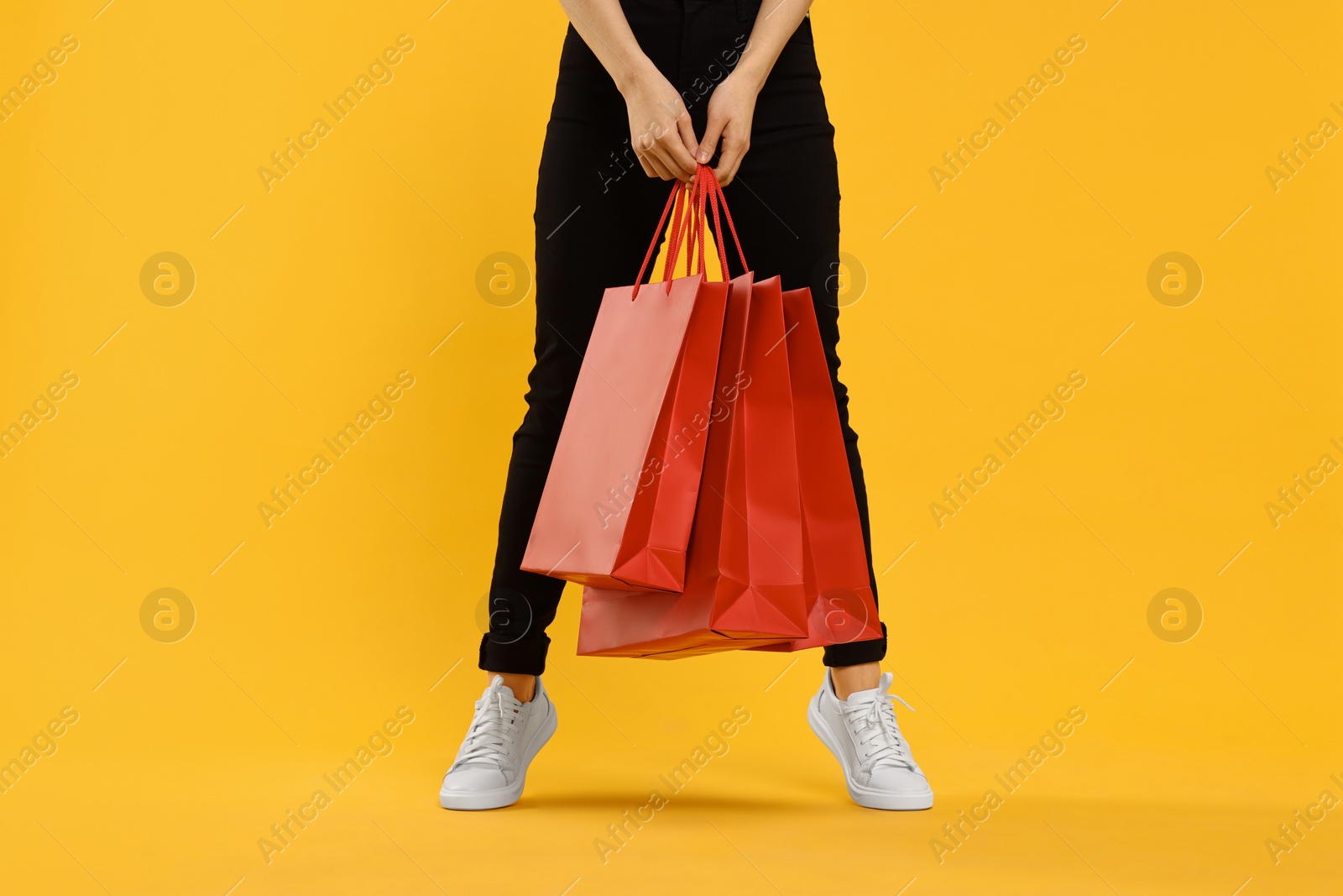 Photo of Woman with shopping bags on yellow background, closeup