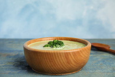 Photo of Delicious broccoli cream soup served on blue wooden table. Space for text