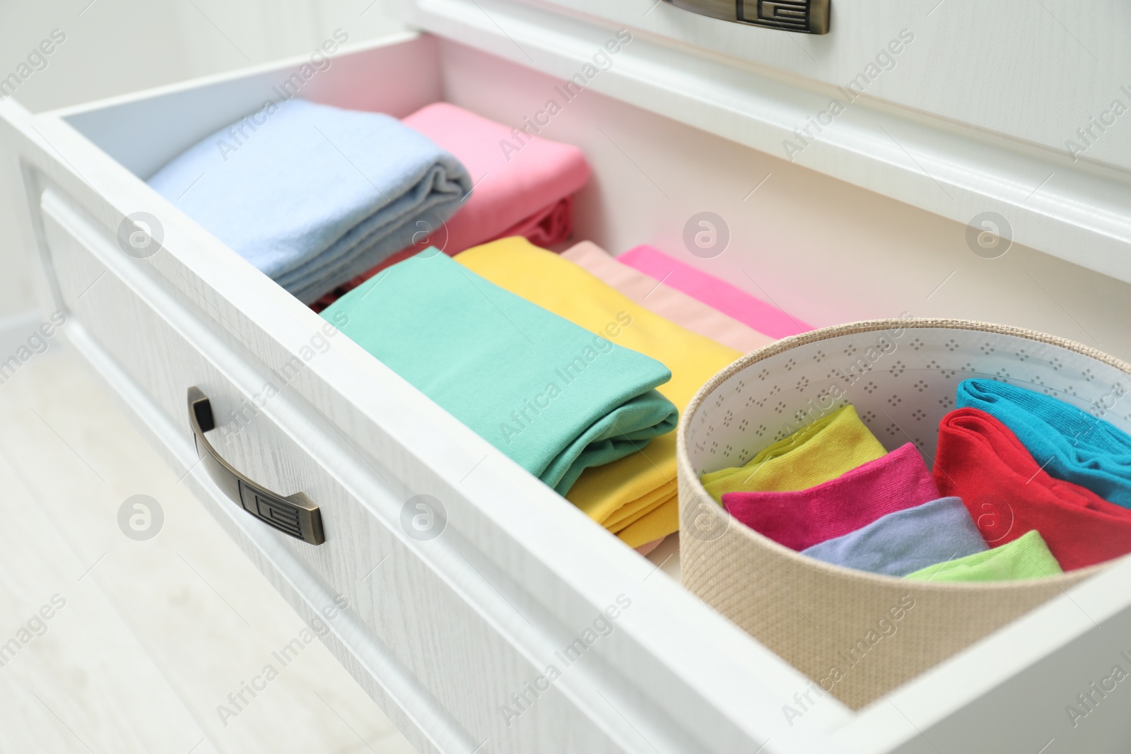 Photo of Chest of drawers with different folded clothes indoors, closeup