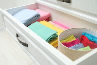 Chest of drawers with different folded clothes indoors, closeup