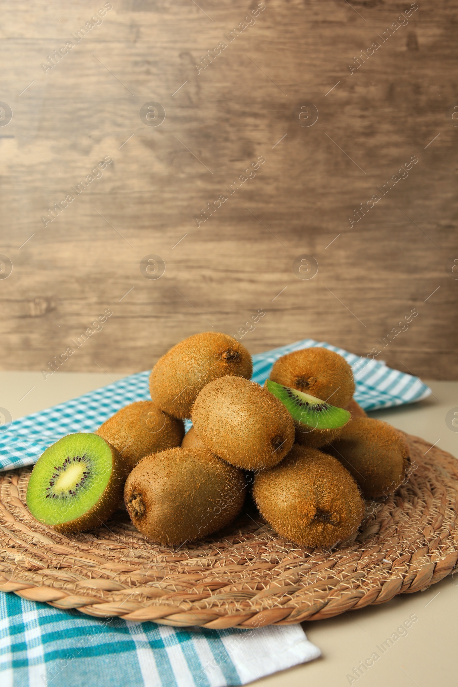 Photo of Heap of whole and cut fresh kiwis on white table, space for text