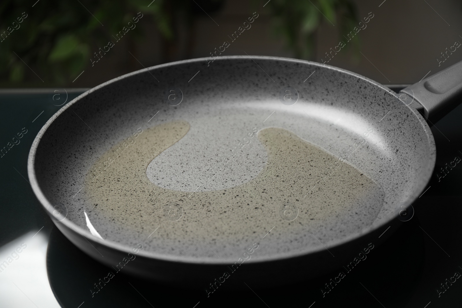 Photo of Frying pan with cooking oil on induction stove