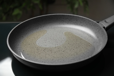 Photo of Frying pan with cooking oil on induction stove