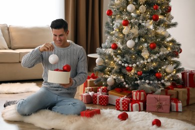 Handsome man decorating Christmas tree at home