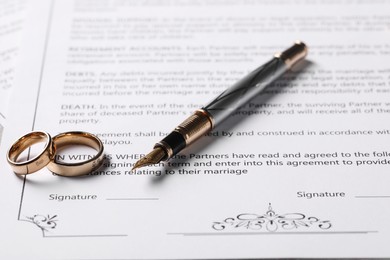 Photo of Marriage contract, fountain pen and golden wedding rings on table, closeup