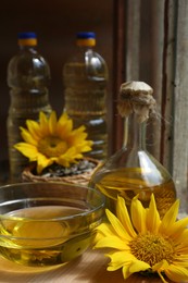 Photo of Organic sunflower oil and flower on wooden table, closeup