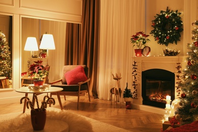 Photo of Beautiful living room interior with burning fireplace and Christmas decor in evening