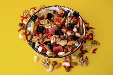 Photo of Bowl with mixed dried fruits and nuts on yellow background