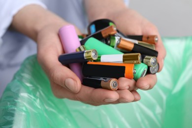 Image of Woman holding many used electric batteries in her hands, closeup