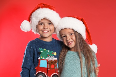 Happy little children in Santa hats on red background. Christmas celebration