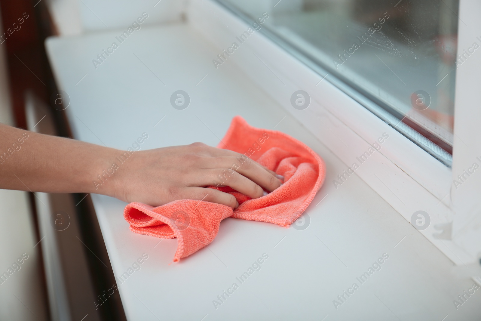 Photo of Woman cleaning window sill with cloth, closeup