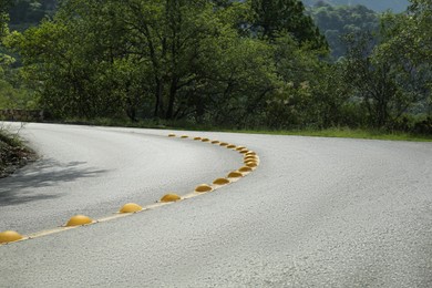 Photo of Asphalt road with yellow line near trees outdoors