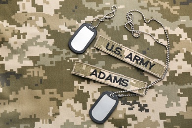 Military ID tags and patches on camouflage background