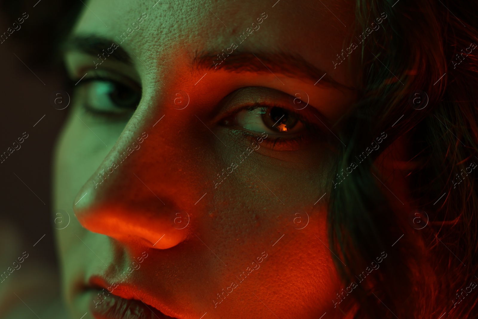 Photo of Portrait of beautiful young woman on color background with neon lights, closeup