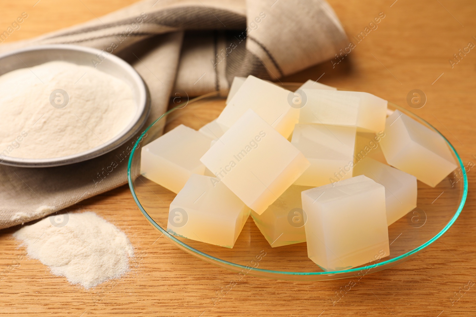 Photo of Agar-agar jelly cubes and powder on wooden table, closeup