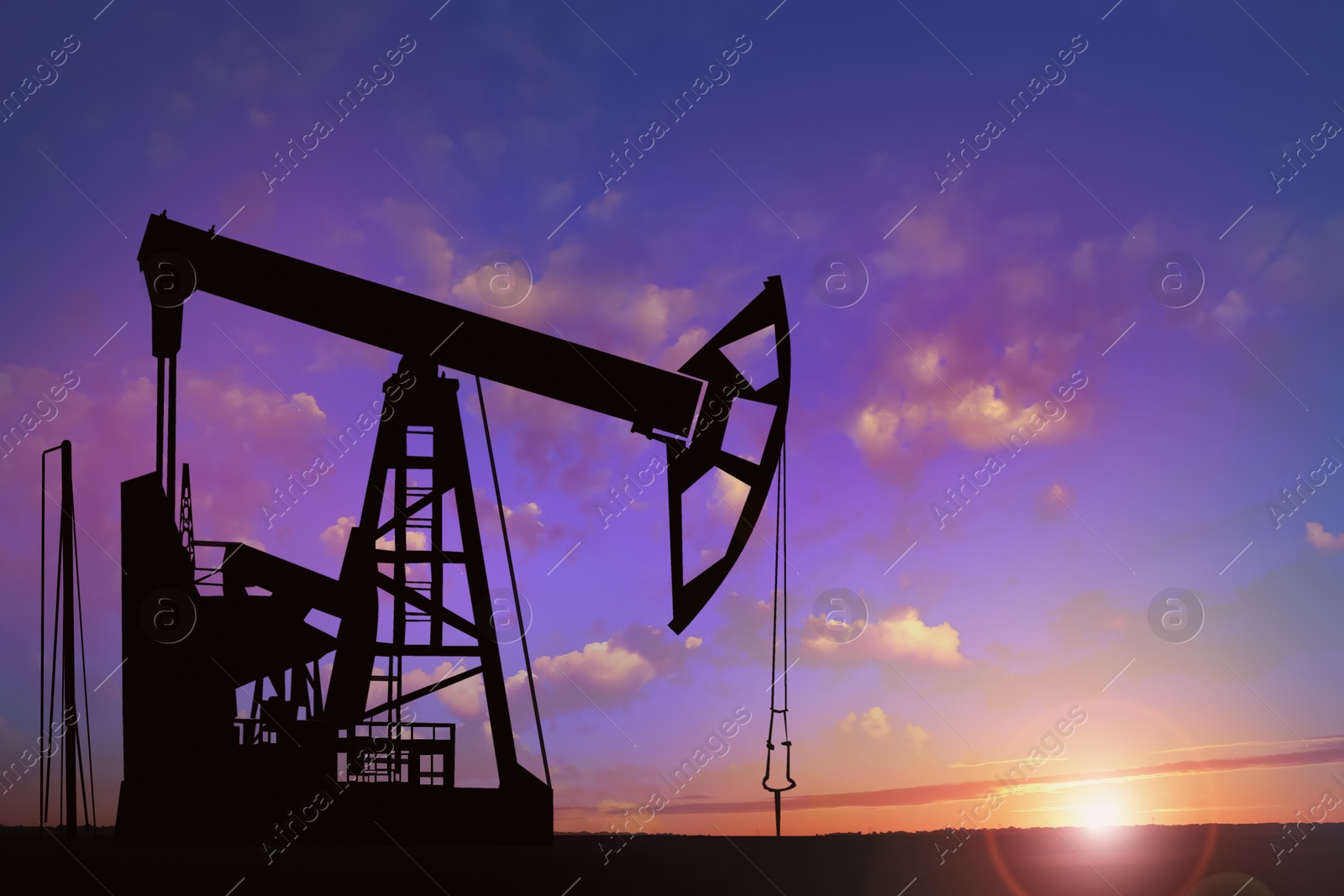 Image of Silhouette of crude oil pump at sunset