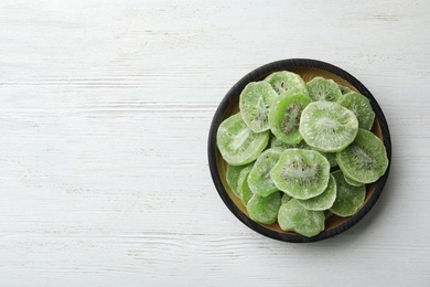 Bowl of dried kiwi on wooden background, top view with space for text. Tasty and healthy fruit