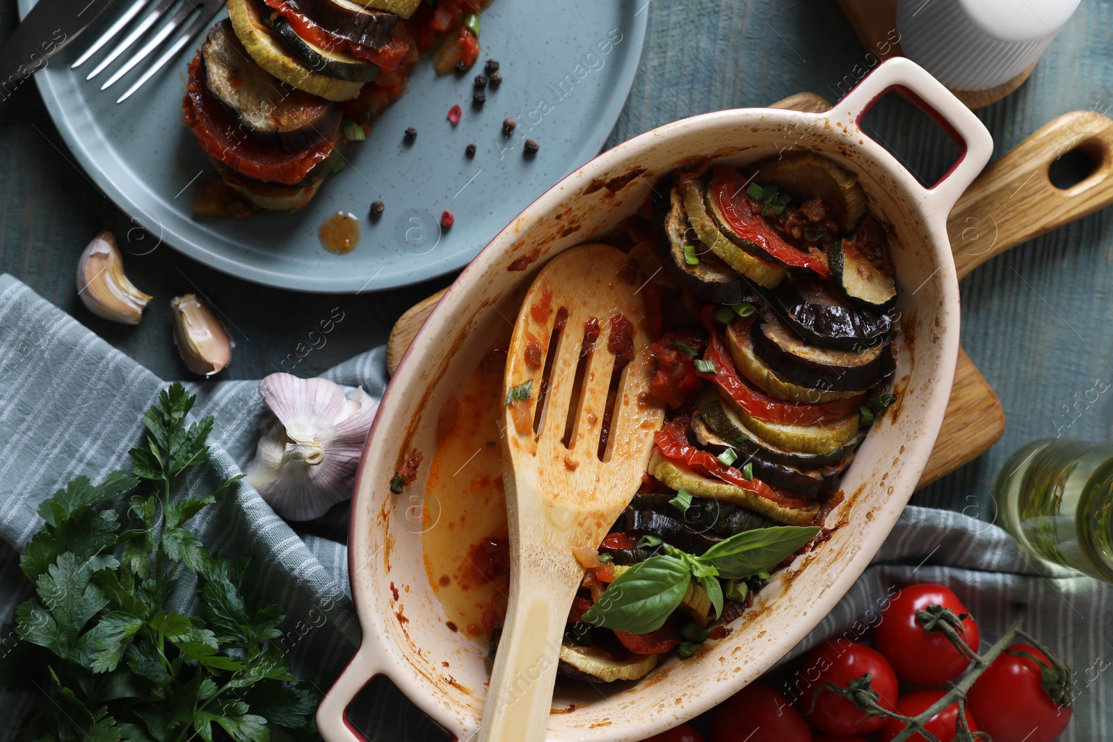 Photo of Delicious ratatouille served with basil on grey wooden table, flat lay