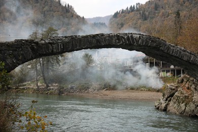 Photo of Adjara, Georgia - November 19, 2022: Picturesque view of stone arched bridge over Acharistskali river in mountains