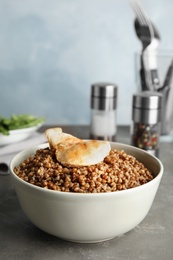 Photo of Tasty buckwheat porridge with meat on grey table