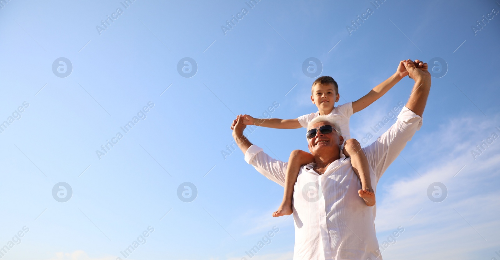 Photo of Cute little boy with grandfather spending time together near sea