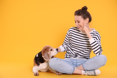Photo of Happy young woman with cute Beagle dog on orange background. Lovely pet