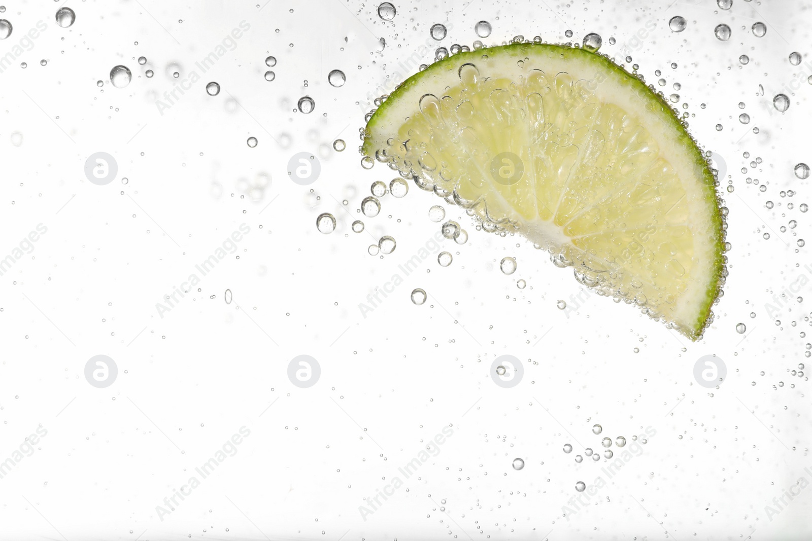 Photo of Juicy lime slice in soda water against white background, closeup. Space for text