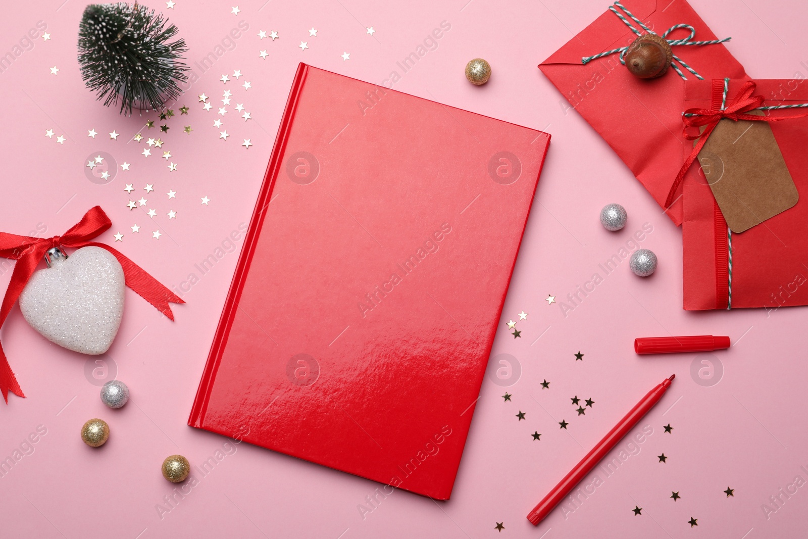 Photo of Red planner and festive decor on pink background, flat lay. New Year aims