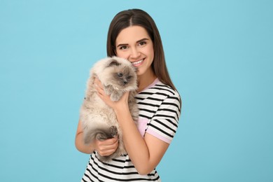 Photo of Happy woman with her cute cat on light blue background