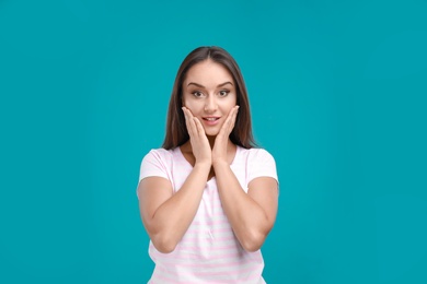 Emotional young woman in casual outfit on turquoise background