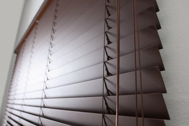 Stylish horizontal window blinds on white wall indoors, closeup