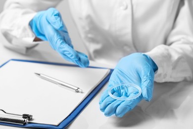 Doctor holding diaphragm vaginal contraceptive ring at table, closeup