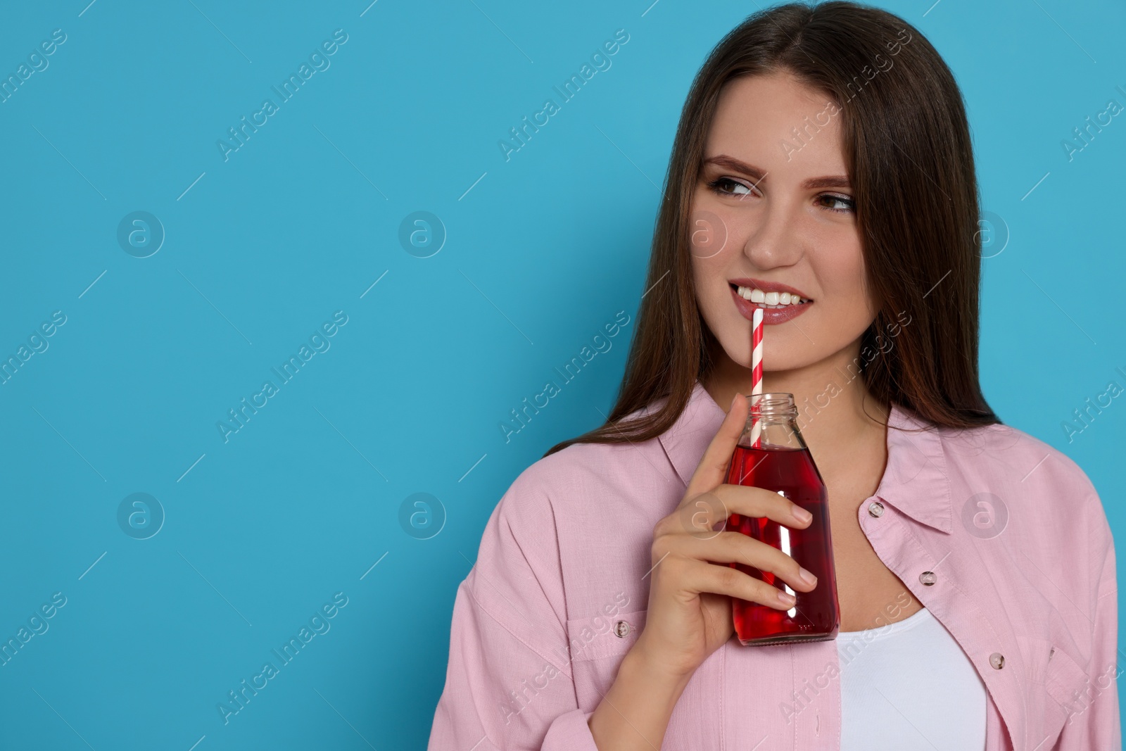 Photo of Beautiful young woman with glass bottle of juice on light blue background. Space for text