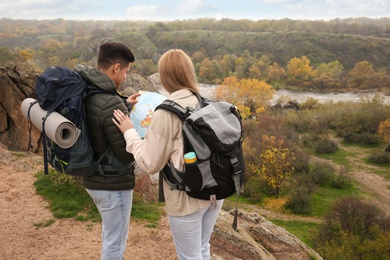 Couple of travelers with backpacks and map planning trip in mountains, back view. Autumn vacation