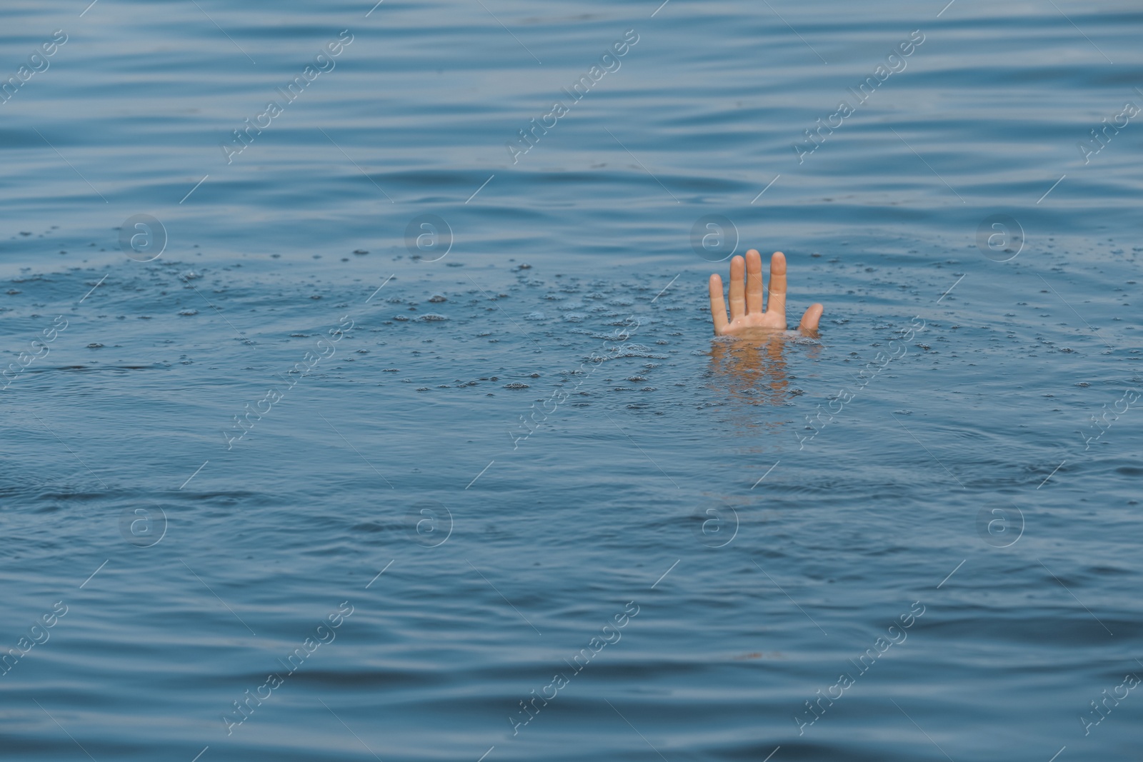 Photo of Drowning man reaching for help in sea, closeup