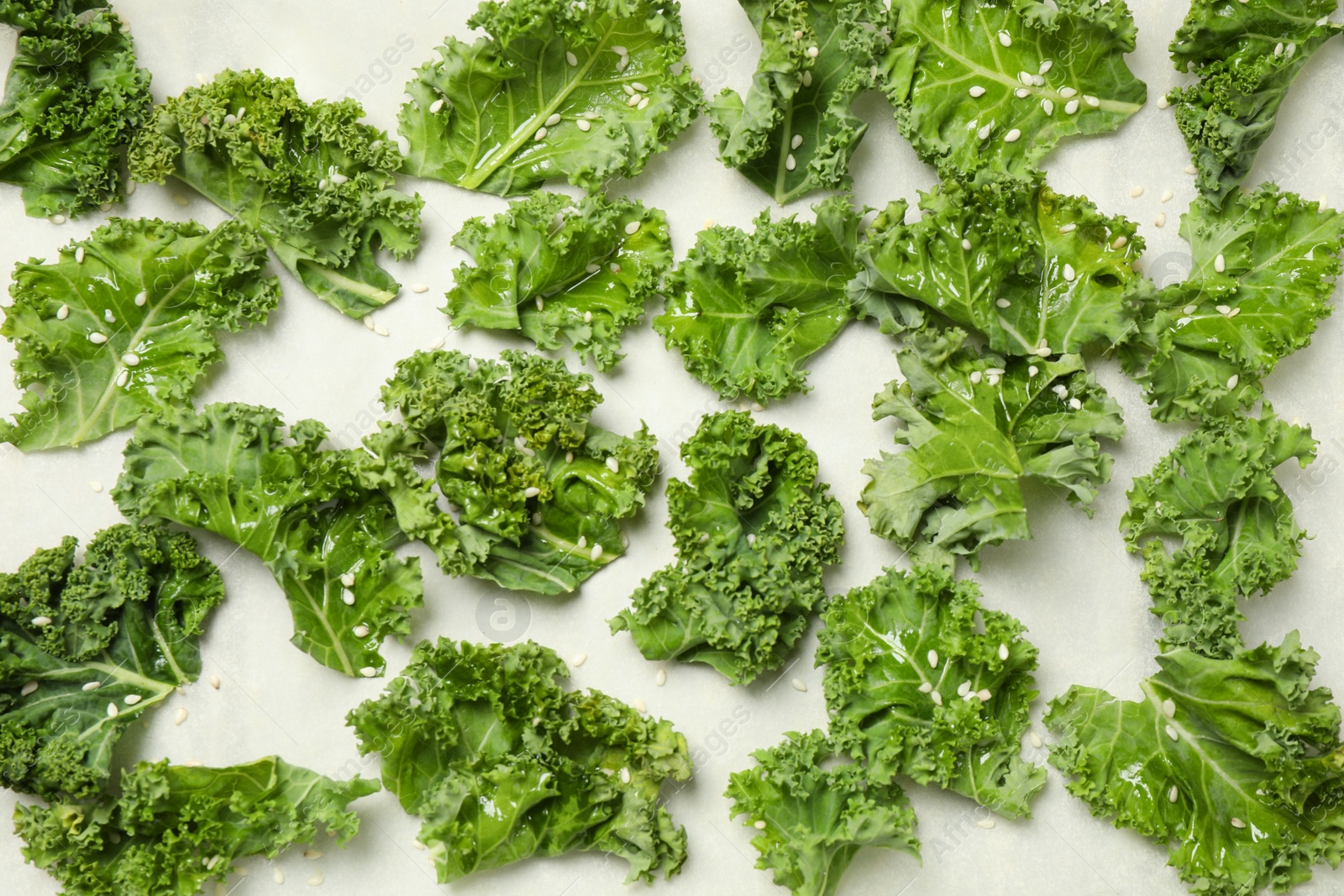 Photo of Raw cabbage leaves on parchment paper, flat lay. Preparing kale chips