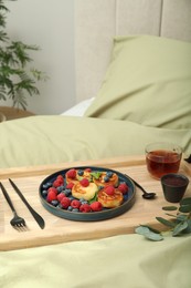 Tasty breakfast served in bedroom. Cottage cheese pancakes with fresh berries and mint on wooden tray